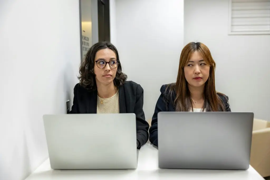 Woman smiling while working at a laptop in a bright home office, suggesting focused, positive work and well-being.